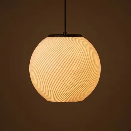 A round pendant with a spiral relief, lit, on a brown backdrop