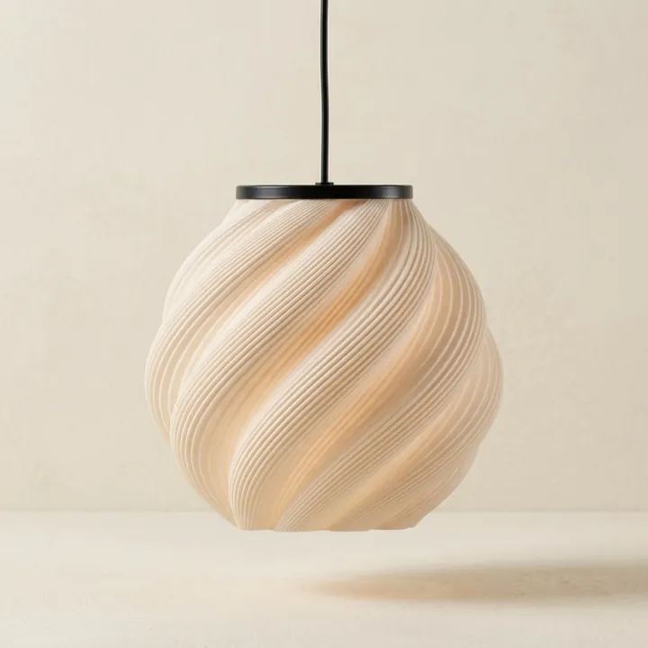 A cream pendant with a twisted relief, hanging against a light wall